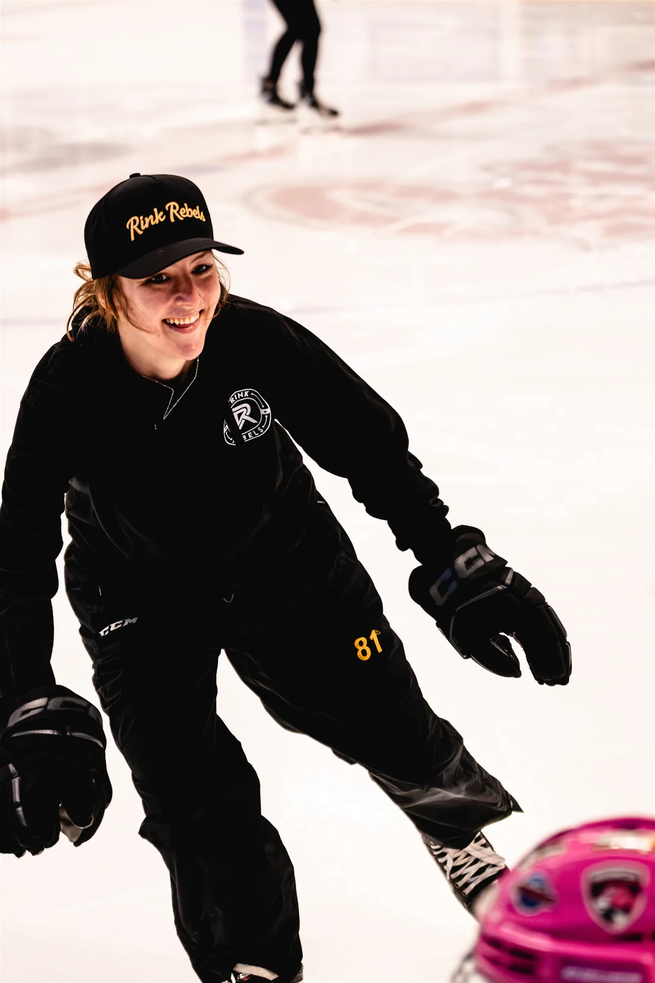 A professional hockey mentor smiling while skating with young Rink Rebels players