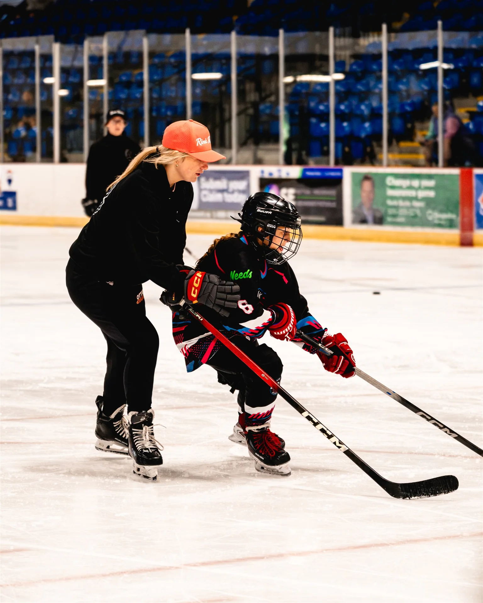 An accomplished athlete mentor guiding a young Rink Rebels player on the ice